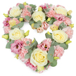 A full, heart-shaped funeral wreath dominates the image, its soft pastel colours standing out gently against a crisp white background, as if displayed in a calm, light-filled Upton Park florist studio. The heart is lush and complete, with no bare spaces, symbolising a love that feels whole even in the midst of grief. Cream and pale yellow roses are placed as focal points throughout, their spiral centres tight and precise, slowly unfurling into larger, rounded blooms that convey grace and dignity. Interlaced among them, light pink carnations bring a lace-like texture; their many frilled petals overlap in layers, softening the overall look and adding a sense of tender comfort. Deeper pink to mauve lisianthus blossoms are dotted around the heart, their slightly open, bell-shaped flowers and subtle variations in shade introducing a gentle depth, like soft evening light. Silvery-green eucalyptus leaves with their smooth, rounded forms cradle the blooms, forming a quiet, cool-toned border that helps define the heart's outline. Small, yellowish-green buds are scattered here and there, catching the eye and suggesting new beginnings even in times of farewell. The composition feels carefully considered, as though created by a local florist who understands how families in Upton Park want to honour a loved one, whether for a church service, crematorium, or a simple remembrance at home. The wreath's blend of roses, carnations, lisianthus, and eucalyptus speaks of peace, remembrance, and enduring affection, making it a fitting tribute for expressing sympathy and love when saying goodbye.